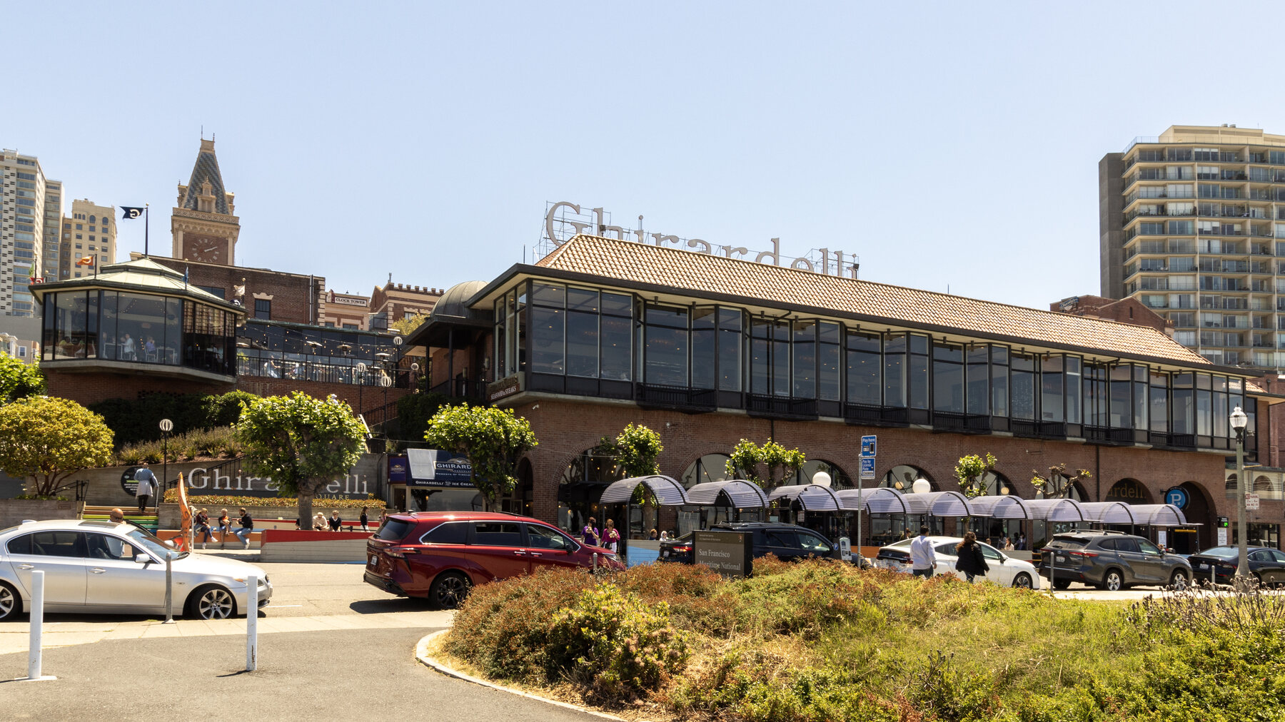 Wide street-level view of Ghirardelli Square in San Francisco with the sign and clock tower visible.